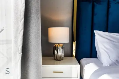 a lamp on a night stand next to a bed at AWS Holiday Homes - Lux Gateaway near Dubai Mall in Dubai