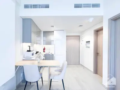 a white kitchen with a table and chairs at Elegant 1BR with Balcony in Azizi Riviera in Dubai