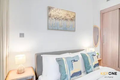 a bedroom with a bed with blue and white pillows at Spacious Azizi Riviera Studio in Dubai
