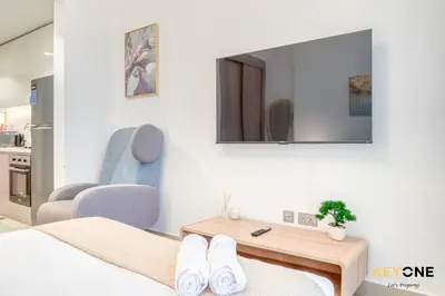 a room with a bed and a table and a mirror at Spacious Azizi Riviera Studio in Dubai