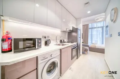 a kitchen with a sink and a washing machine at Spacious Azizi Riviera Studio in Dubai