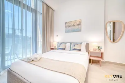 a bedroom with two beds and a large window at Spacious Azizi Riviera Studio in Dubai