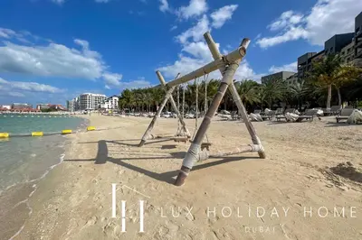 a beach with a swing on the sand at LUX The Dream Palm Atlantis Sea View Suite in Dubai
