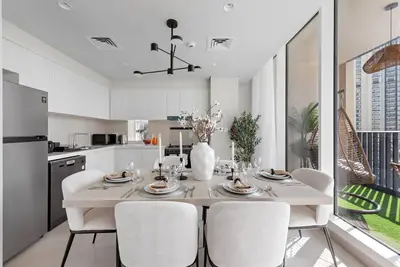 a white kitchen with a dining table and chairs at FIRST CLASS 2BR Stylish Bliss in Dubai
