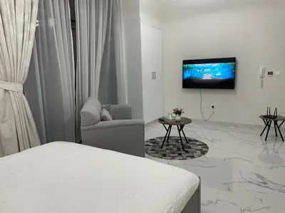 a white room with a bed and a tv on a wall at Luxury & Comfort in Majan A Dubai Delight in Dubai
