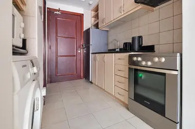 a kitchen with a stove and a red door at Sunny Studio Perfect For Discovery Gardens Stays in Dubai