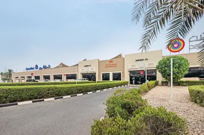 a shopping mall with a palm tree in front of it at Sunny Studio Perfect For Discovery Gardens Stays in Dubai