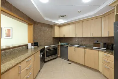 a large kitchen with wooden cabinets and stainless steel appliances at DVH Al Hamri Jumeirah Shoreline 2 Bed & Maids Free beach access in Dubai