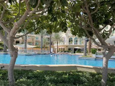 a large swimming pool with trees in front of a building at DVH Al Hamri Jumeirah Shoreline 2 Bed & Maids Free beach access in Dubai