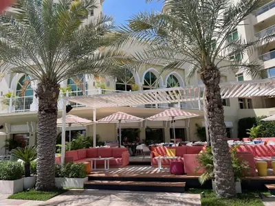 a resort with palm trees and red chairs and tables at DVH Al Hamri Jumeirah Shoreline 2 Bed & Maids Free beach access in Dubai