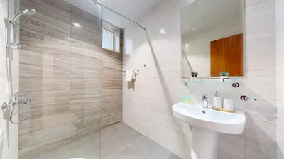 a white bathroom with a sink and a shower at Vacationer I Sophisticated 1 Bedroom Apartment I Steps from Dubai Mall & Burj Khalifa I Dunya Tower in Dubai