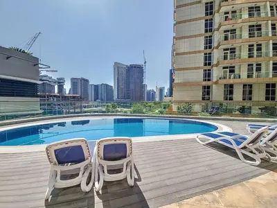 two chairs and a swimming pool in a city at Vacationer I Sophisticated 1 Bedroom Apartment I Steps from Dubai Mall & Burj Khalifa I Dunya Tower in Dubai