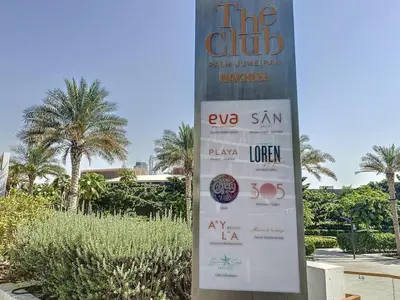 a sign in front of a building with palm trees at Seven Hotel and Apartment - Chic Studio in the Palm in Dubai