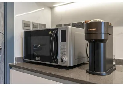 a microwave sitting on a counter next to a coffee maker at Bright Resort Style Studio Amenities Samana GA by Vibel in Dubai