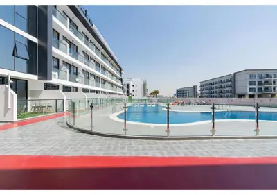 a swimming pool in front of a building at Bright Resort Style Studio Amenities Samana GA by Vibel in Dubai