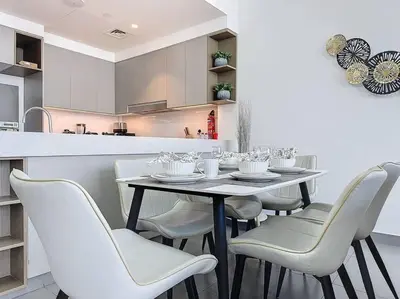 a dining room table with white chairs in a kitchen at FAM Living - Spacious 3-Bedroom Apartment in Creek Gate with Stunning Views in Dubai