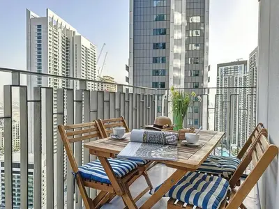 a table and chairs on a balcony with a view of a city at FAM Living - Spacious 3-Bedroom Apartment in Creek Gate with Stunning Views in Dubai
