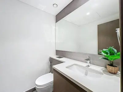 a bathroom with a sink and a toilet and a mirror at FAM Living - Spacious 3-Bedroom Apartment in Creek Gate with Stunning Views in Dubai
