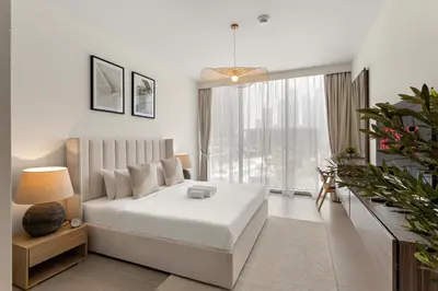 a white bedroom with a bed and a large window at Superb 1Bed With Pool & Gym near the Burj Khalifa in Dubai