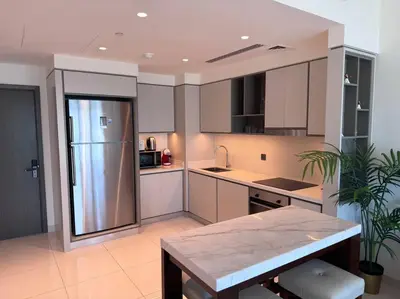 a kitchen with white cabinets and a stainless steel refrigerator at 2 Bed - Sunrise Bay Views in Dubai