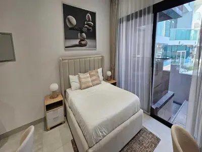 a bedroom with a bed and a large window at Luxury Studio in Jumeirah Village Circle in Dubai