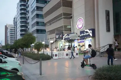 a woman riding a scooter in front of a building at Pathfinder Partition Room in Barsha Heights Tecom in Dubai