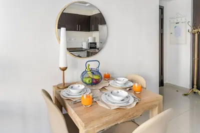 a dining room table with a mirror and a table with chairs at FIRST CLASS Studio Cozy Urban Retreat in Dubai