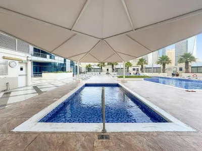 a swimming pool with an umbrella in a building at FIRST CLASS Studio Cozy Urban Retreat in Dubai