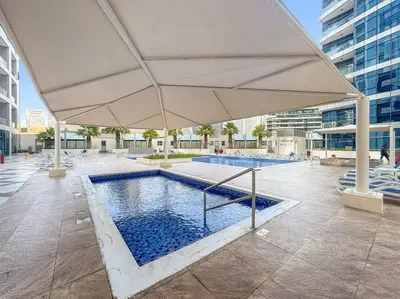 a large white umbrella over a swimming pool at FIRST CLASS Studio Cozy Urban Retreat in Dubai