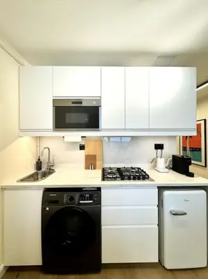 a kitchen with white cabinets and a stove top oven at Brand New Studio - Comfy & WFH in Dubai