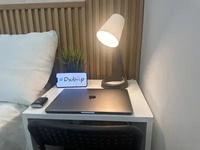 a desk with a laptop and a lamp on a bed at Quiet Partition Room in Tecom Barsha Heights in Dubai