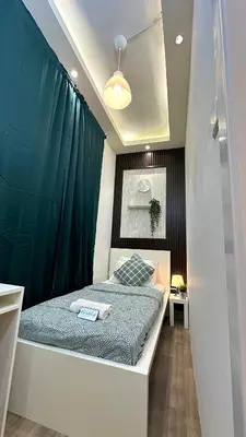 a small bedroom with a bed and a green curtain at Metropolis View Partition Room Near Internet City Metro in Dubai