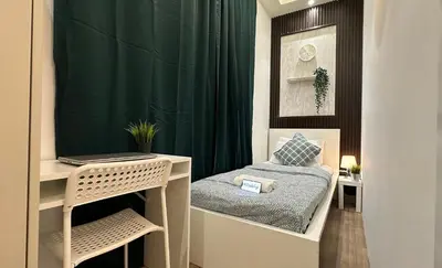 a bedroom with a bed and a desk with a laptop at Metropolis View Partition Room Near Internet City Metro in Dubai