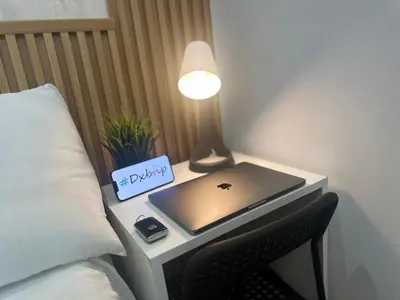 a laptop on a table next to a bed at Metropolis View Partition Room Near Internet City Metro in Dubai