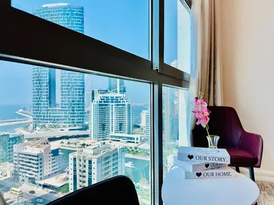 a room with a window with a chair and a table at Elite Waterfront 3BR Haven - Marina and Sea Views! in Dubai