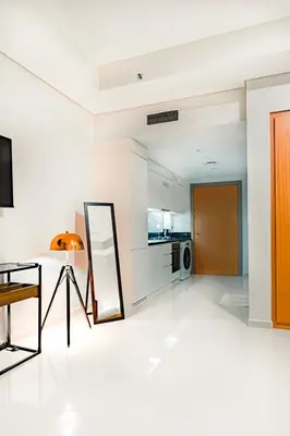 a white living room with a table and a mirror at High rise studio near Dubai Mall in Dubai