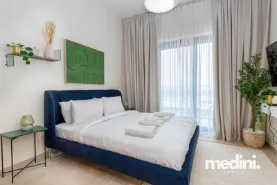 a bedroom with a blue bed with towels on it at Cozy Studio in Azizi Riviera - Dubai in Dubai