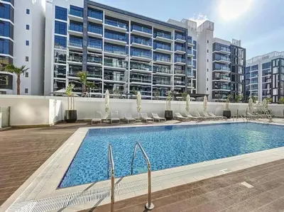 a swimming pool in front of a large building at Cozy Studio in Azizi Riviera - Dubai in Dubai