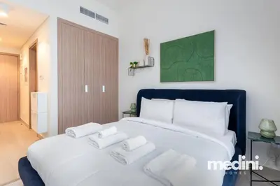 a bedroom with a large white bed with three pillows at Cozy Studio in Azizi Riviera - Dubai in Dubai