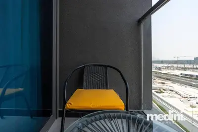 a yellow chair sitting on a balcony with a window at 15th Northside - Studio - Dubai in Dubai