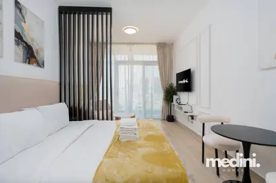 a bedroom with a white bed and a table and a desk at Studio in Bloom Height - JVC - Dubai in Dubai