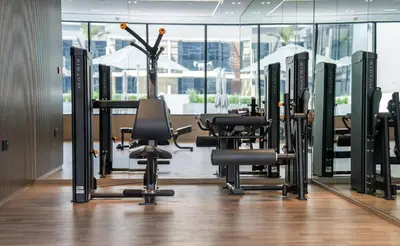 a gym with a row of treadmills and chairs at Serene 1BR Haven with Pool View in Binghatti Corner! in Dubai