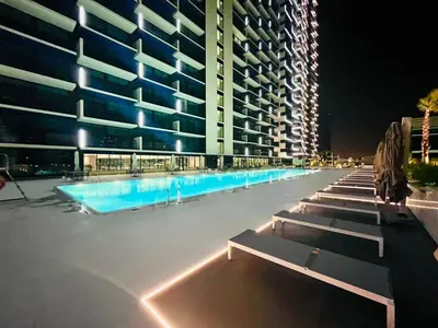 a swimming pool in front of a building at night at Serene 1BR Haven with Pool View in Binghatti Corner! in Dubai