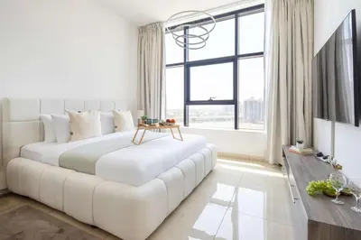 a white bedroom with a large white bed and a large window at Frank Porter - Square Tower in Dubai