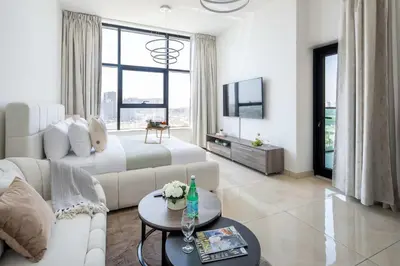 a white living room with a couch and a tv at Frank Porter - Square Tower in Dubai