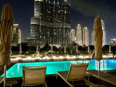 a pool with chairs and a city skyline at night at The Address Residences Dubai Opera, Full Burj Khalifa View, 2BR Downtown Luxury in Dubai