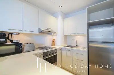 a kitchen with white cabinets and a stainless steel refrigerator at LUX The Silverene Marina View Studio 1 in Dubai