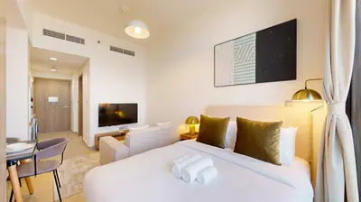 a bedroom with a white bed and a living room at Azizi Riviera 29 - Aesthetic Studio in Meydan in Dubai