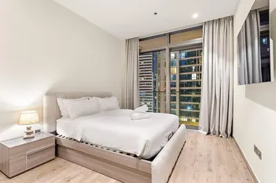 a bedroom with a white bed and a large window at Dubai Marina 1BR with Pool Near Shops & Restaurants in Dubai