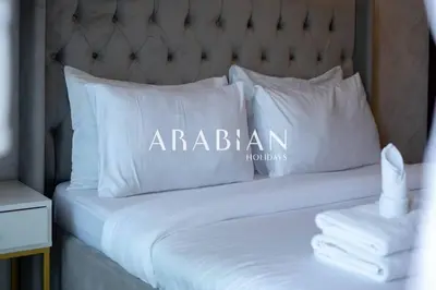 a bed with a white pillow with the word arabian on it at Cozy 1BR Apartment with Balcony in Business Bay in Dubai
